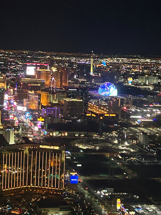 Las Vegas Strip at night with city lights and skyline, including Mandalay Bay and The Sphere glowing in the distance
