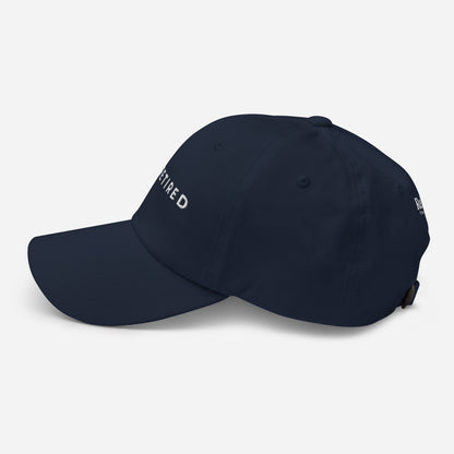 Navy embroidered I’m Retired travel dad hat from Retired Traveler (Left)